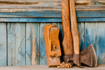 Old tools. Axe and plane on a vintage wooden background, with space for text