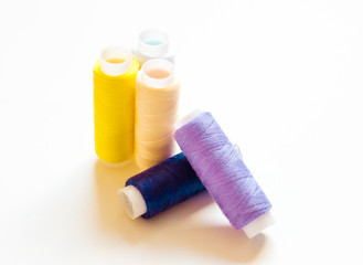 multicolored spools of thread on white background