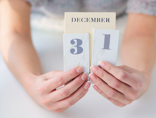 Woman hands with beautiful french manicure holding calendar open on December 31