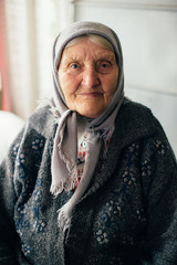 portrait of a smiling old grandmother in a handkerchief in her old house