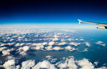 Fototapeta premium clouds in rows from aircraft with deep blue sky with land and sea below