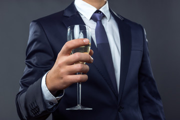 Businessman holding a glass of champagne over gray background