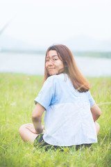 Young woman sitting at relax pose or freedom pose or chill pose on the meadow during sunrise at morning. Riverside.