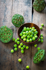 Lotus seeds in red wood bowl and calyx on wood background