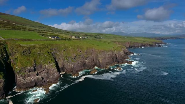 Closer aerial shot of the village of Dingle a small island fronting the big sea with some green fields on it in Ireland