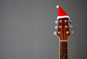 Red Christmas hat on guitar with grey background, Merry Christmas song