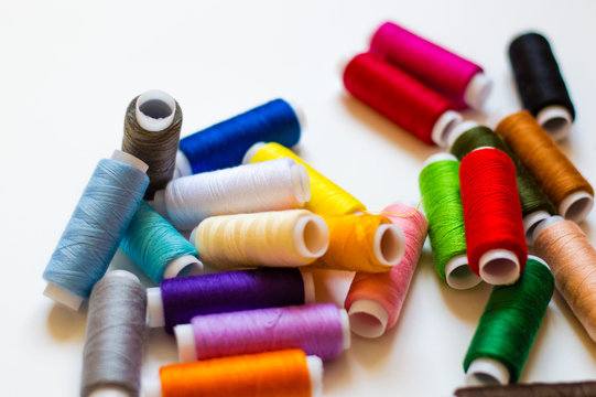 multicolored spools of thread on white background