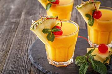 Glasses of pineapple juice with pieces of pineapple