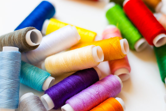 multicolored spools of thread on white background