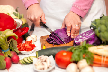 Obraz na płótnie Canvas Slicing of red cabbage on chopping board with a knife