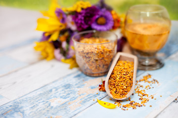 Pollen in wooden scoop, plastic glass and liquid state on the ta