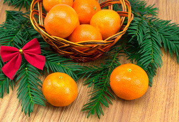 Ripe tangerines in the wicker basket, a sprig of tree with red b