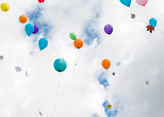 Multicolored balloons with maple leaves fly in the sky.