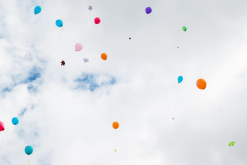 Multicolored balloons with maple leaves fly in the sky.