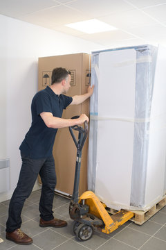 Mature Man Moving Huge Cartons With Trolley