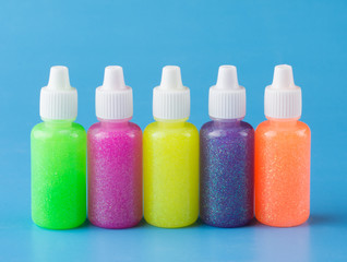 Glitter glue in bright colors for crafts, on blue background