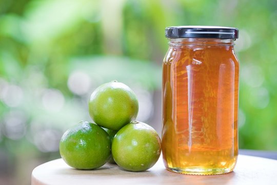 Honey in glass jar and lime on wood table natural background