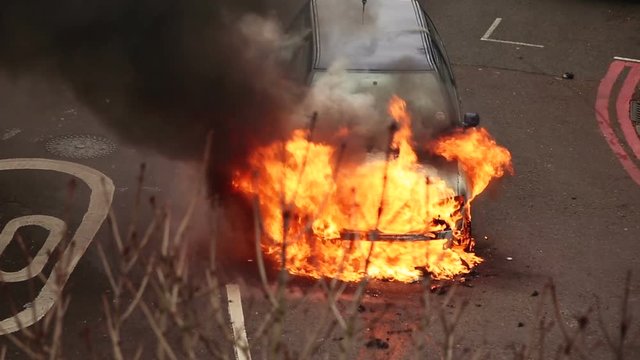 Telephoto shot of a car being engulfed by flames after an accident
