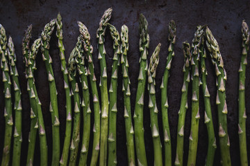 fresh asparagus spears on a dark metal surface