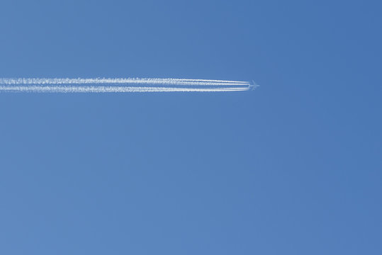 Airplane with condensation trails on blue sky