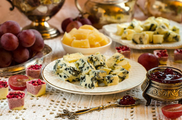 Cheeses, fruits and desserts on the plates
