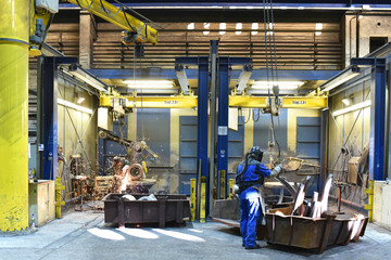 Arbeiter in einer Industriehalle - schweißen und flexen von Werkstücken/ Gussteilen aus Metall