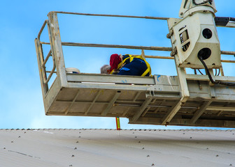 Worker repairs metal cover on a small passenger basket crane trucks