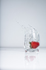 strawberry splash into water glas on white background