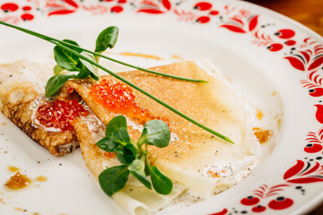 Fototapeta na wymiar Russian pancakes with red caviar on plate closeup.