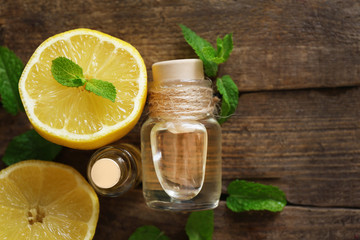 Essential oil with mint and lemon on wooden table