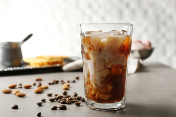 Glass of cold coffee with beans and nuts on table