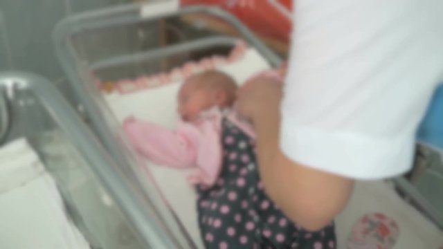 Nurse swaddles newborn infant in medical chamber