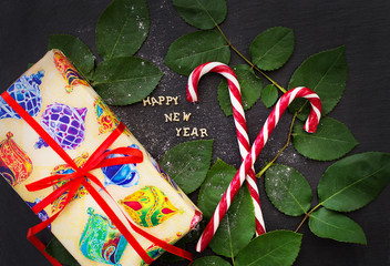 inscription of new year on a black board with gift and red candy
