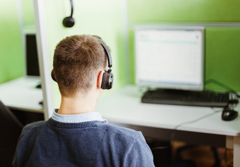 Young man seating against monitor display of desktop computer. Gambling and contact center concept.