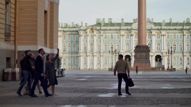 Group of tourists with a guide on a background of Palace Square