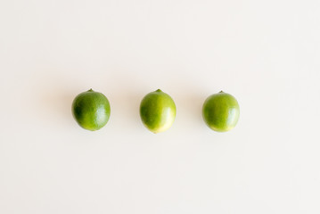 High angle view of three green limes on white table
