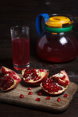 pomegranate juice with sliced pomegranate on a wooden board.