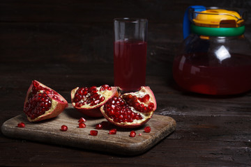 pomegranate juice with sliced pomegranate on a wooden board.