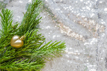 Dekoration zu Weihnachten, ein Tannenzweig mit einem kleinen golden Herz auf silbernem Stoff mit...