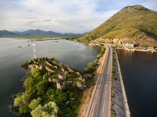 Fototapeta na wymiar Aerial view at the dam with railroad and vehicular bridge leading through the Skadar lake and Lesendro fortress. Route from Podgorica to Adriatic coast. Montenegro