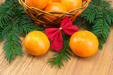 Ripe tangerines in the wicker basket, a sprig of tree with red b