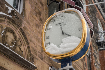 Street retro clock covered in snow and ice in winter