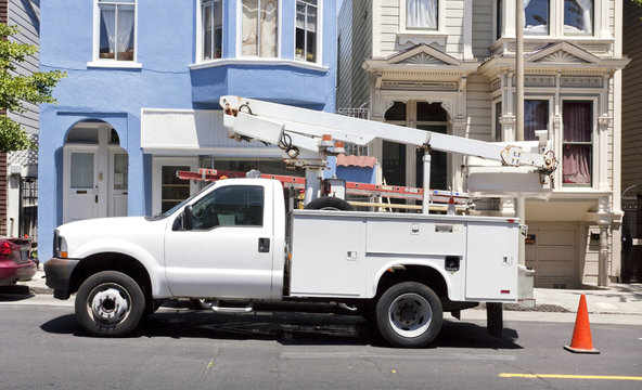 Parked utility truck with cherry picker truck. Horizontal.