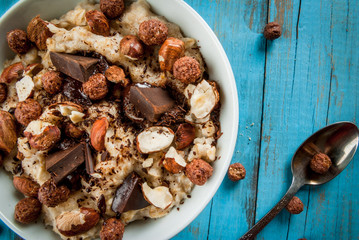 Nourishing and delicious breakfast, oatmeal with hazelnuts, dark chocolate and a chocolate corn balls. Copy space