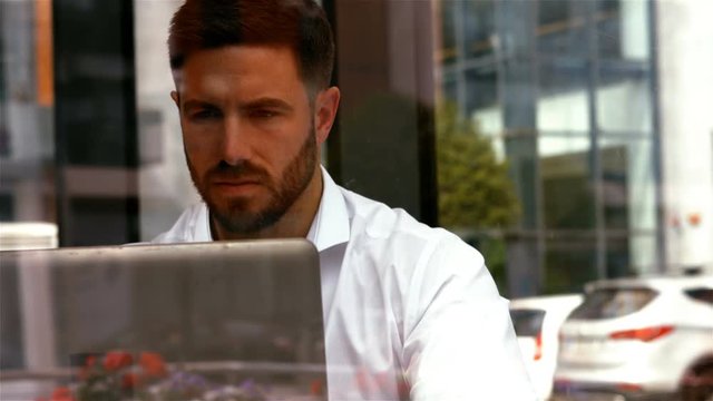 Businessman having a cup od coffee while using laptop