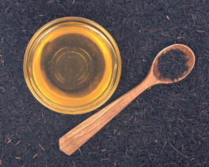 Organic amish farm pure honey in bowl and camellia assam tea with wooden spoon