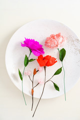 Pink handmade paper flower on big decorative ceramic platter
