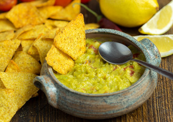 Guacamole in home crafted bowl on natural wooden desk.