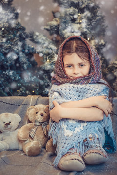 Cute little girl covered in warm scarf waiting for Christmas