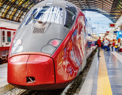 Fototapeta Trenitalia Frecciarossa (red arrow) on platform of Milan Central Station. This high speed train can reach 300 km/h and operate Turin-Milan-Bologna-Florence-Rome-Naples route. Passanger staying nearby.